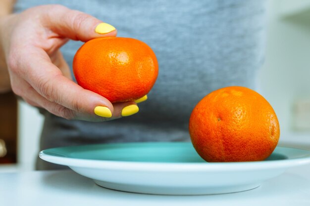 Las manos de la mujer con la manicura brillante pel de mandarina fresca