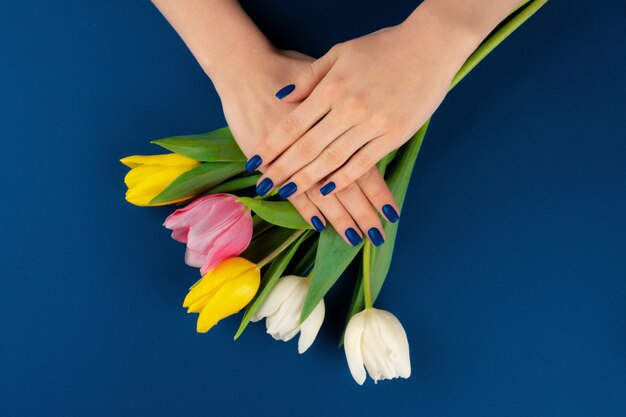 Manos de mujer con manicura con coloridos tulipanes