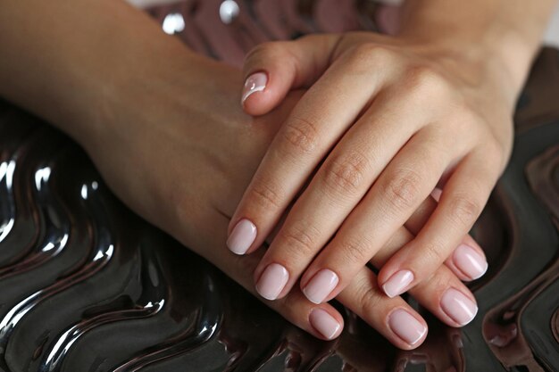 Manos de mujer con manicura francesa en primer plano de superficie brillante
