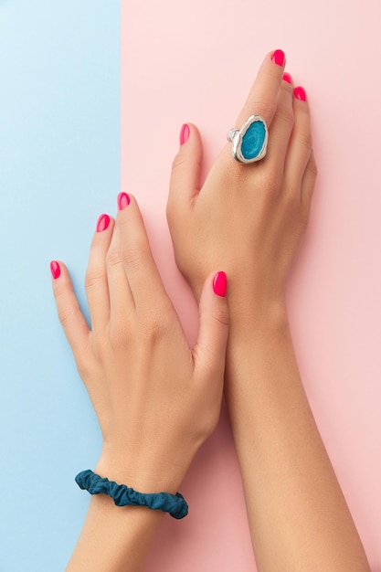 Manos de mujer con manicura de moda en concepto de salón de belleza de doble fondo rosa y azul