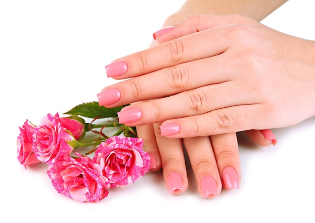 Manos de mujer con manicura rosa y flores aisladas en blanco