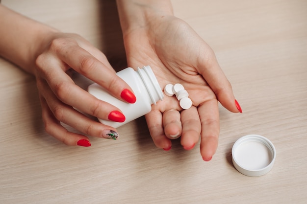 Las manos de una mujer, en las manos de unas pastillas grandes, blancas y redondas en sus manos. Medicamentos vitamínicos