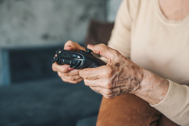 Manos de mujer mayor en casa concepto de jubilación sentado jugando videojuegos emocionado primer plano Relación de actividad Estilo de vida feliz