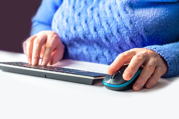 Las manos de una mujer mayor escribiendo en un teclado de pc de cerca. pensionista trabajando desde casa. el concepto de aprendizaje de personas mayores a la alfabetización informática o habilidades de internet.