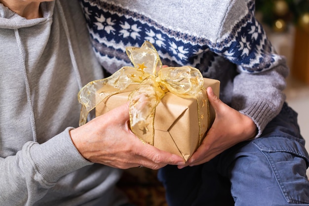 Manos de mujer mayor y un niño con regalo de Navidad