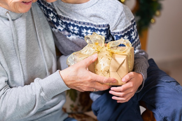 Manos de mujer mayor y un niño con regalo de Navidad