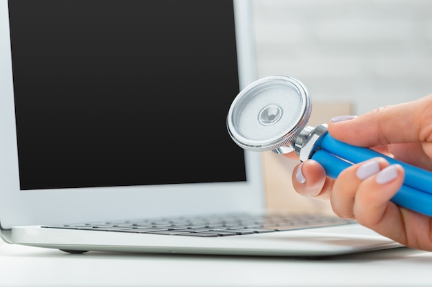 Manos de mujer médico con laptop.