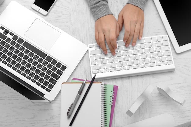 Foto las manos de la mujer en la mesa con computadora, tableta, teléfono inteligente y otras cosas vista superior