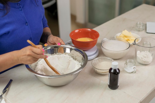 Manos de mujer mezclando harina con ingredientes para hacer pan en casa