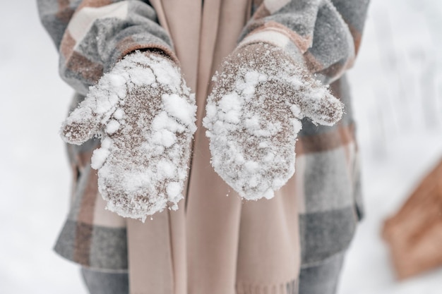 Manos de mujer en mitones para sujetar la nieve.