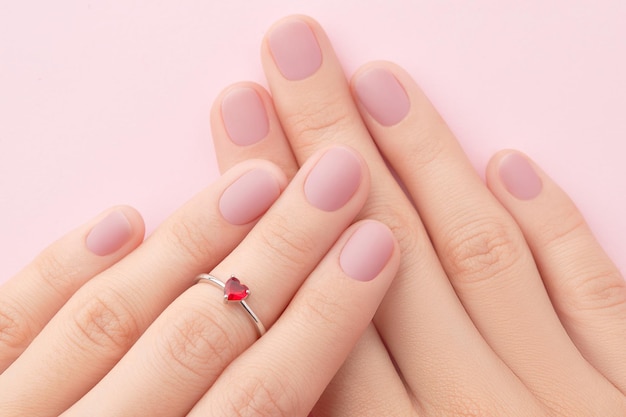 Las manos de la mujer con la moda rosa mate manicure de cerca salón de belleza