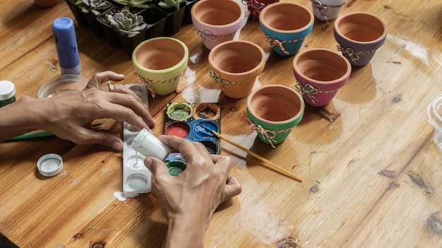 Manos de una mujer mulata latina pintando ollas de barro para plantar plantas suculentas