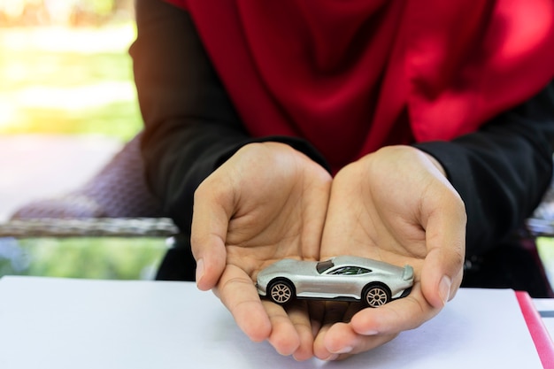 Manos de mujer musulmana de negocios sosteniendo el coche