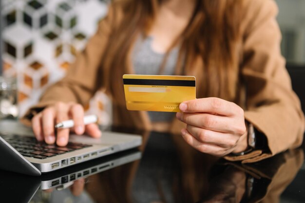 Manos de mujer de negocios usando un teléfono inteligente y sosteniendo una tarjeta de crédito con un diagrama de efecto de capa digital como concepto de compras en línea