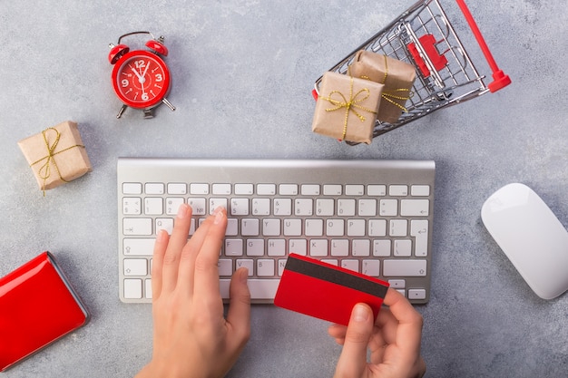 Manos de mujer ordenando regalos en línea, pagando con tarjeta de crédito