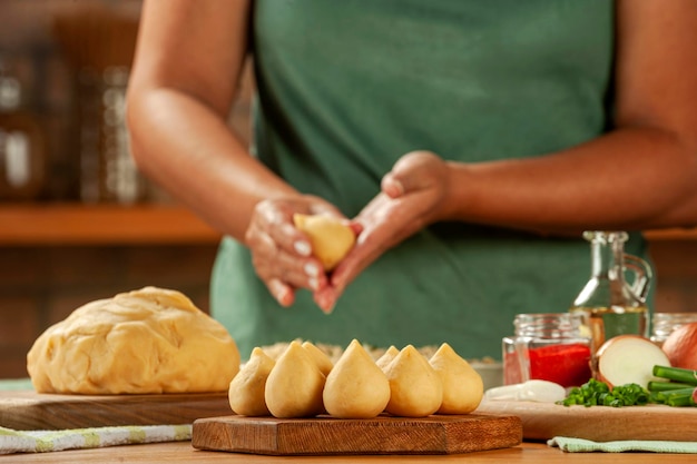 Foto manos de mujer preparando croqueta brasileña coxinha de frango en una mesa de madera