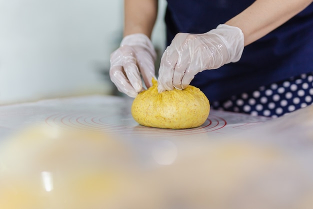 Manos de mujer preparando masa de pan en la mesa de la cocina.