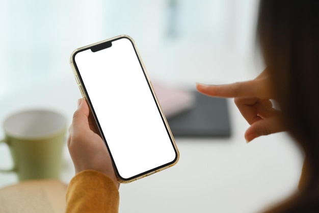 Las manos de la mujer de primer plano sosteniendo un teléfono móvil con pantalla vacía para publicidad o mensaje