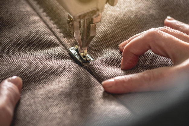 Manos de mujer en el proceso de coser en equipo profesional Tejido de costura en producción Primer plano