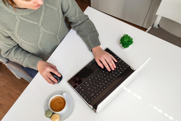 Manos de una mujer que trabaja en una computadora con una taza de café