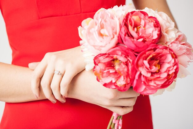 manos de mujer con ramo de flores y anillo de bodas.