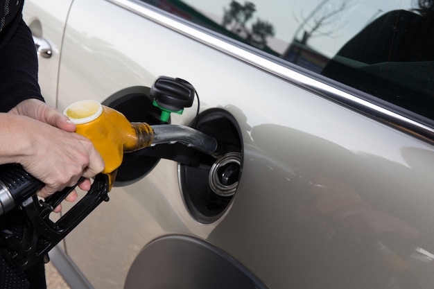 Manos de mujer reabasteciendo su auto en la gasolinera