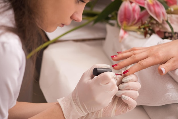 Manos de mujer recibiendo una manicura en un salón de belleza. Limado de uñas. Primer plano, enfoque selectivo.