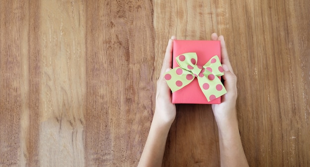 Manos de mujer con regalo en la mesa de madera