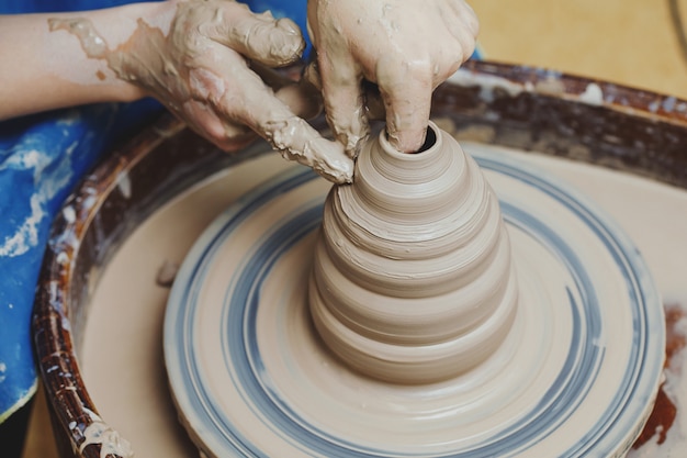 Manos de mujer en la rueda de alfarería. Artesano artista formas olla