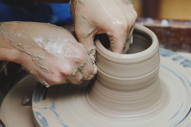 Manos de mujer en la rueda de alfarería. Artesano artista formas olla