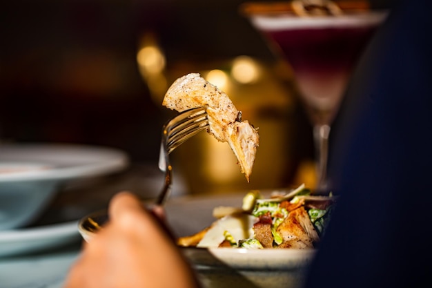 Manos de mujer sentadas en la mesa del restaurante sosteniendo un tenedor y listas para comer ensalada césar