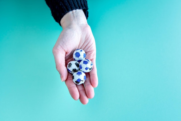 Manos de mujer sosteniendo balones de fútbol de chocolate