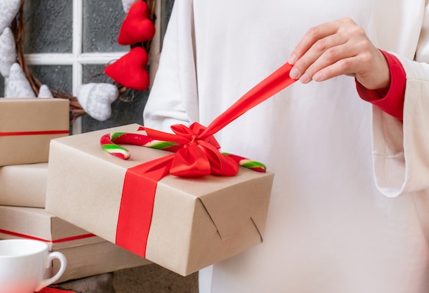 Manos de mujer sosteniendo caja de regalo con cinta roja