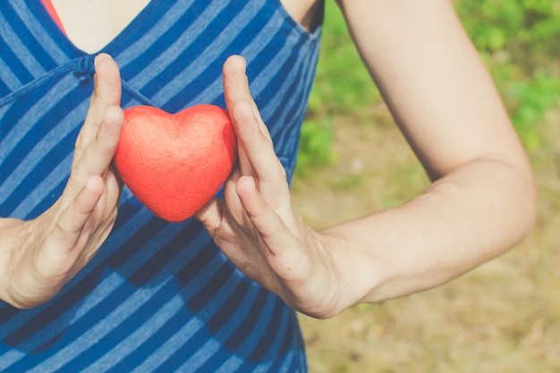 manos de mujer sosteniendo corazón rojo