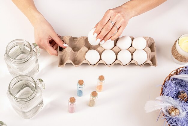 Manos de mujer sosteniendo un huevo blanco listo para colorear el huevo de pascua vista superior