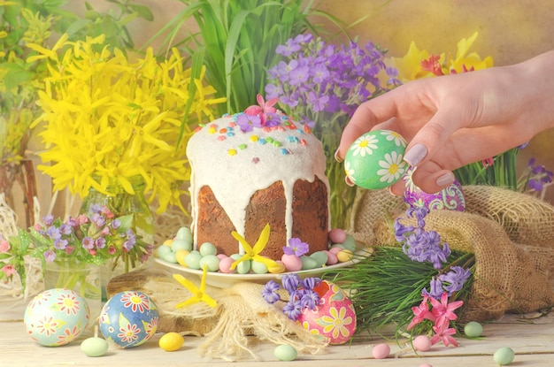 Manos de mujer sosteniendo huevo de Pascua Decoración de mesa para vacaciones de Pascua