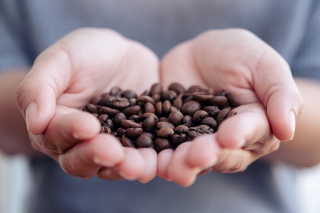 manos de mujer sosteniendo y mostrando granos de café