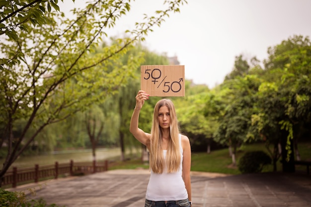 Manos de mujer sosteniendo una pancarta con símbolo masculino y femenino