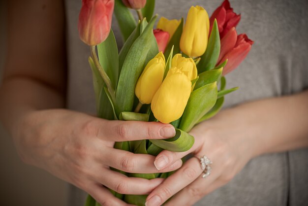 Manos de mujer sosteniendo ramo de flores de tulipán de cerca