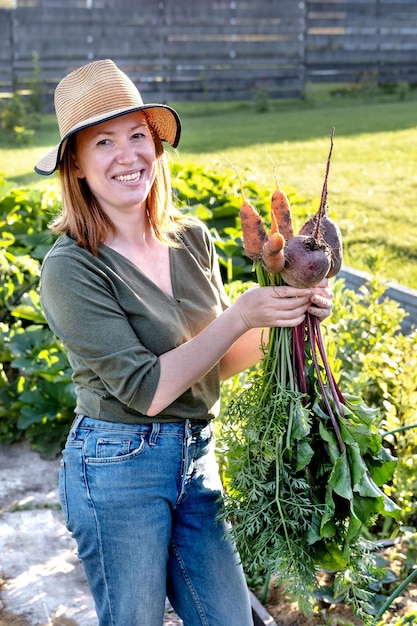 Manos de mujer sosteniendo remolacha fresca y zanahoria en las manos al atardecer Concepto de cultivo de nutrición natural en crecimiento por su propio proceso de trabajo real en el jardín
