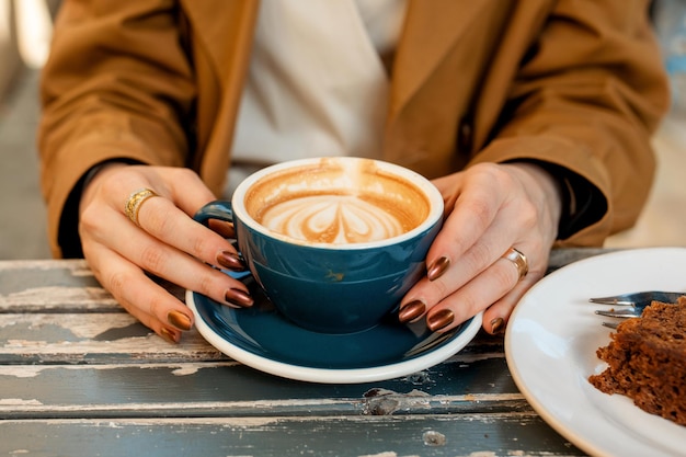 Manos de mujer sosteniendo una taza de café en la cafetería