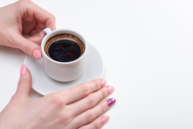 Manos de mujer sosteniendo una taza de café exprés