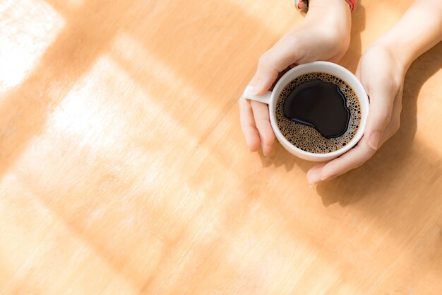 Manos de mujer sosteniendo la taza de café con leche