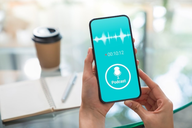 Foto manos de mujer sosteniendo un teléfono inteligente y escuchando podcast con aplicación de forma de onda en el móvil