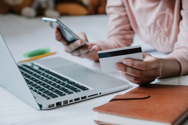 Manos de mujer sosteniendo el teléfono inteligente y usando tarjeta de crédito para compras en línea