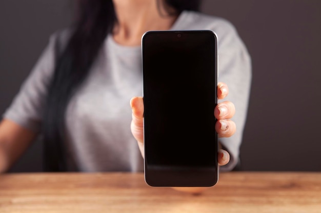 manos de mujer sosteniendo un teléfono móvil negro con pantalla blanca en blanco