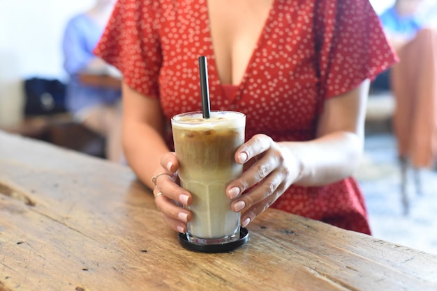 Manos de mujer sosteniendo un vaso de café helado