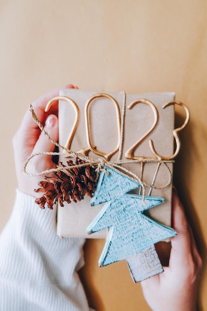 Foto manos de mujer sostienen caja hecha a mano de regalo decorada de navidad o año nuevo imagen tonificada