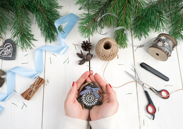 Las manos de una mujer sostienen un pequeño árbol de Navidad de madera.