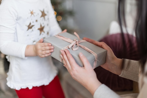 Las manos de la mujer sostienen un regalo de Navidad Una madre le da un regalo a un niño Feliz Navidad y Próspero Año Nuevo